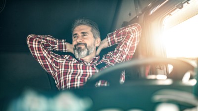 Un conductor se sienta relajado frente al volante de su camión